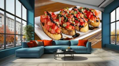 The Bruschetta is beautifully presented on a white plate in an inviting dining setting, topped with fresh diced tomatoes, basil, and balsamic drizzle. Wall mural