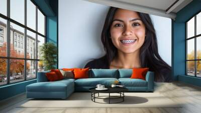 Young Hispanic girl wearing a t-shirt and jeans at a family function sporting dental braces with crossed arms looking at the camera. She displays a happy face and is smiling with crossed arms. Wall mural