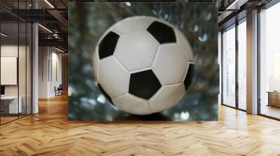 Classic soccer or football ball in focus. Busy background with glitter abstract bokeh. Sport theme image. Wall mural