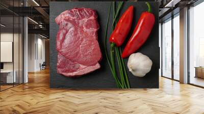 Fresh uncooked red sirloin steak on a dark slate plate and red chilli peppers and garlic bulb, fresh herbs. Wall mural