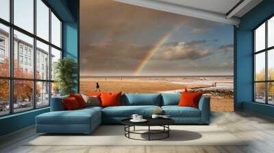 Kids on a sandy beach and two rainbows in the dramatic sky over the ocean. Wall mural