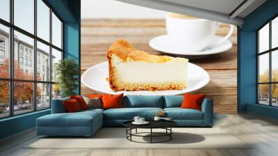 Piece of a cheesecake on a white saucer and cup of espresso on wooden table. Shallow focus. Wall mural