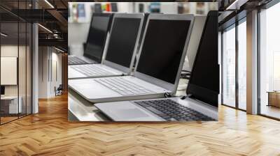 A row of laptops in computer shop. Closeup, selective focus Wall mural