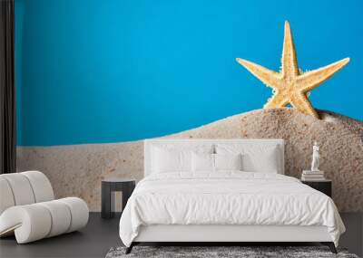 Starfish stands in the sand on a blue background Wall mural