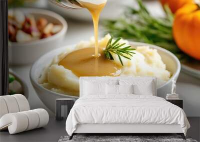 Close-up of mashed potatoes with gravy being served at a Thanksgiving dinner, with other dishes in the background Wall mural