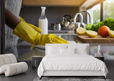  A woman's hand in a yellow protective glove wipes the kitchen counter with a white cloth. Kitchen cleaning concept Wall mural