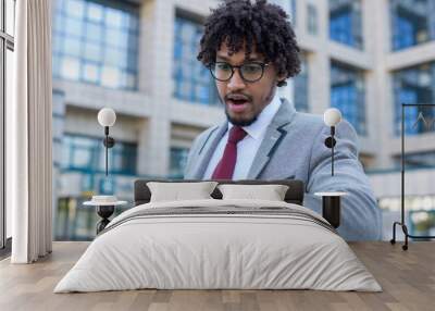 Beautiful young business man late for work looking at his watch shocked Wall mural