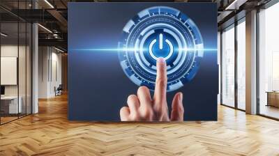 Close-up of a finger pressing a glowing blue power button  Wall mural