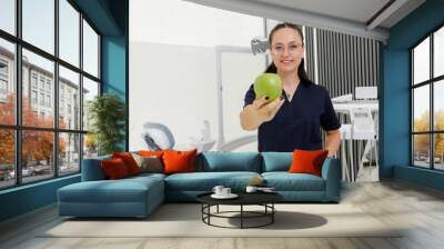 Dental professional offers a green apple in a modern dental clinic during a health awareness event Wall mural