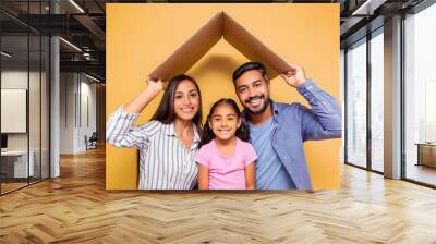 Happy multiethnic family with child holding cardboard roof Wall mural