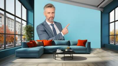 Middle-aged businessman pointing finger isolated on light blue background with copy space Wall mural