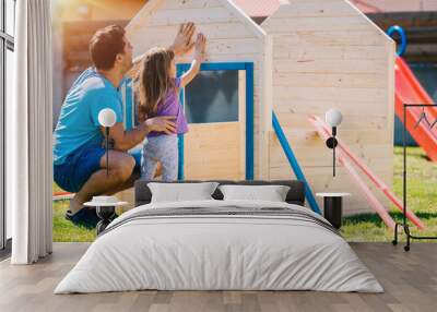 Dad building assembling wooden playhouse with daughter at home in the backyard garden Wall mural