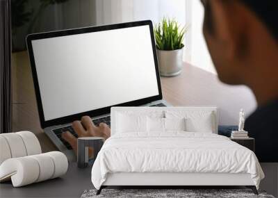 Over shoulder shot of a young man using computer laptop in front of an blank white computer screen in home Wall mural