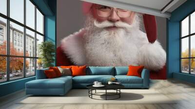 Santa Claus in eyeglasses is looking at camera and smiling, on gray background  Wall mural