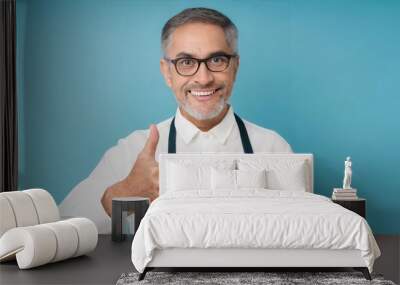 Senior man standing over isolated blue background doing happy thumbs up gesture with hand Wall mural