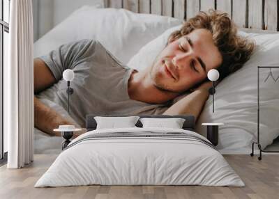 Sleepy man rests comfortably in white bed Wall mural