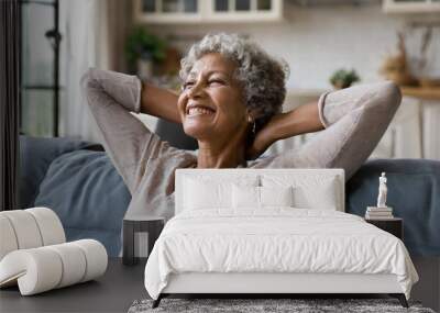 Smiling relaxed mature old woman resting dreaming sitting on couch at home Wall mural