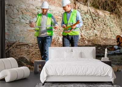 Two Construction Workers Measuring a Log in a Forest Clearing Wall mural