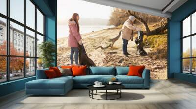 Two volunteers cleaning up the trash from a riverside Wall mural