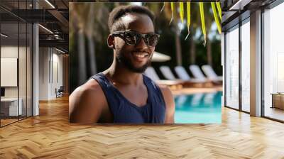 Young man in swimsuit and sunglasses near swimming pool at tropical resort  Wall mural