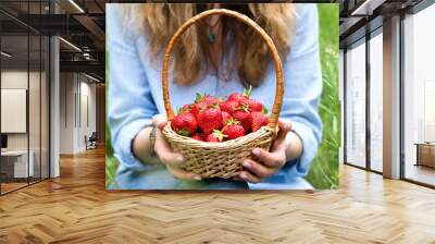 A young woman holds a basket of ripe strawberries. Healthy food. Selective focus. Wall mural