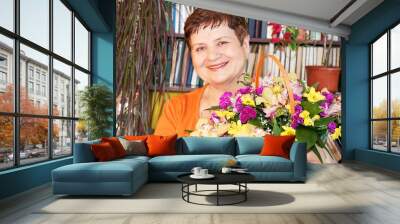 Happy senior woman with basket of flowers. Wall mural