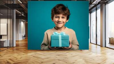 Medium shot portrait photography of a happy kid male holding a gift against a turquoise blue background. With generative AI technology Wall mural