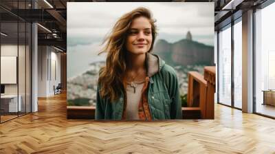 Photography in the style of pensive portraiture of a grinning girl in her 20s wearing a stylish varsity jacket at the christ the redeemer in rio de janeiro brazil. With generative AI technology Wall mural