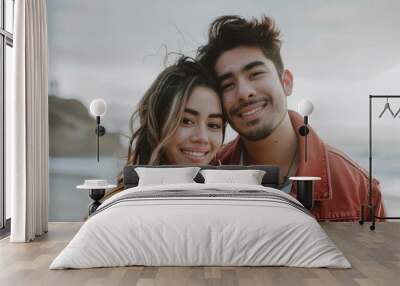 Portrait of a blissful latino couple in their 20s wearing a trendy bomber jacket on sandy beach background Wall mural