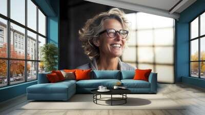 Portrait of a glad woman in her 50s laughing isolated on empty modern loft background Wall mural