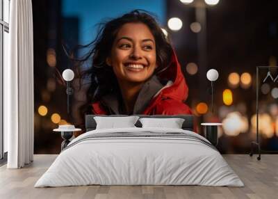 Portrait of a joyful indian woman in her 30s wearing a functional windbreaker isolated on background of bright city lights Wall mural