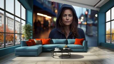 Portrait of a merry woman in her 30s sporting a comfortable hoodie isolated in bustling city street background Wall mural