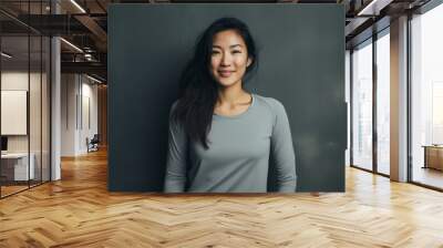 Portrait of a smiling asian woman in her 20s sporting a breathable mesh jersey over bare monochromatic room Wall mural