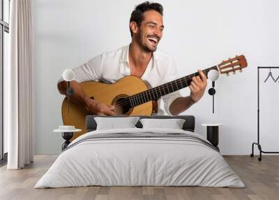 Portrait of a smiling man in his 30s playing the guitar over white background Wall mural