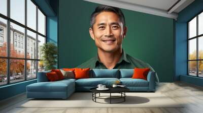 Portrait of a tender asian man in his 40s smiling at the camera isolated in solid color backdrop Wall mural