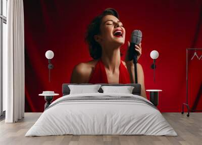 Portrait of a tender woman in her 30s dancing and singing song in microphone in solid color backdrop Wall mural