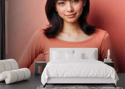 A beautiful Asian woman in an orange t-shirt on an orange background Wall mural