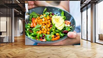 Clean eating, vegan healthy salad bowl closeup , woman holding salad bowl, plant based healthy diet with greens, chickpeas and vegetables Wall mural