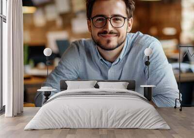 Young businessman architect smiling sitting at his desk with blueprints in a luminous office Wall mural