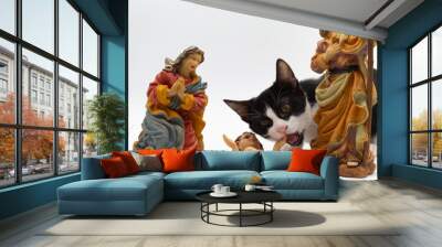 Small black and white cat playing with the figures of the Portal de Belén. Figures of the birth of Christ. Christmas decoration Wall mural