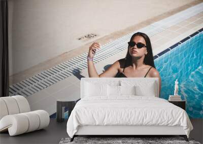 Fashion portrait of graceful cute girl in stylish sunglasses posing in the pool during holidays on luxury resort. Cheerful plus size teenage girl enjoying. happy, positive emotion, summer style. Wall mural