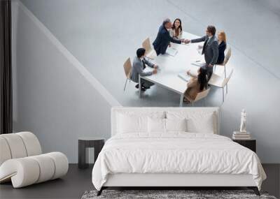 Businessmen in meeting shaking hands across table Wall mural