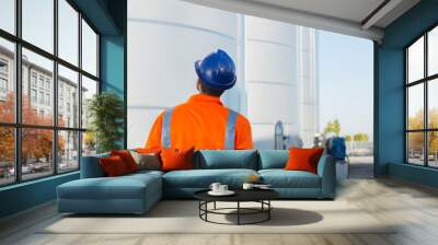 Worker looking up at silage storage towers Wall mural