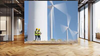 Workers talking by wind turbines in rural landscape Wall mural