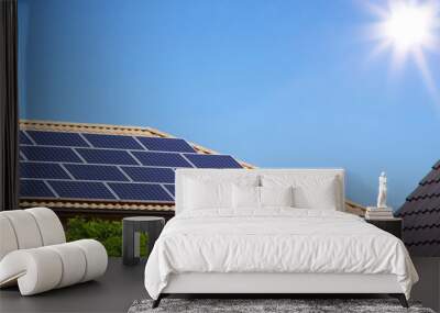 Photovoltaic panels on the roof of a residential building for alternative energy production in front of blue sky with sunshine and copyspace Wall mural