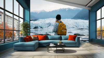 Young woman in denim jacket and backpack walking on glacier in Alaska Wall mural