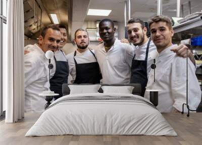 Multi racial cooking team posing for a team photo in the kitchen at work Wall mural