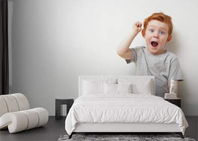 Over excited redhead boy cheering on a white background Wall mural