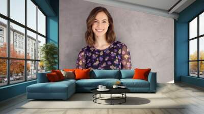 Portrait of a brunette caucasian woman smiling and looking beautiful standing isolated over grey concrete background. Elegant and attractive young female girl looking happy in camera. Wall mural