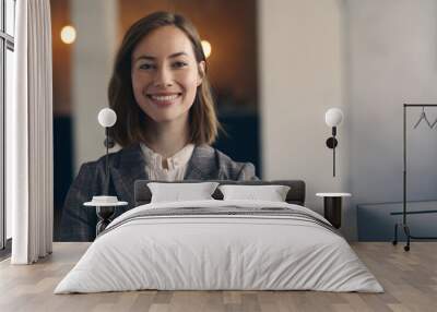 Portrait of attractive businesswoman in a suit smiling and looking into the camera while standing in her office looking professional.  Wall mural